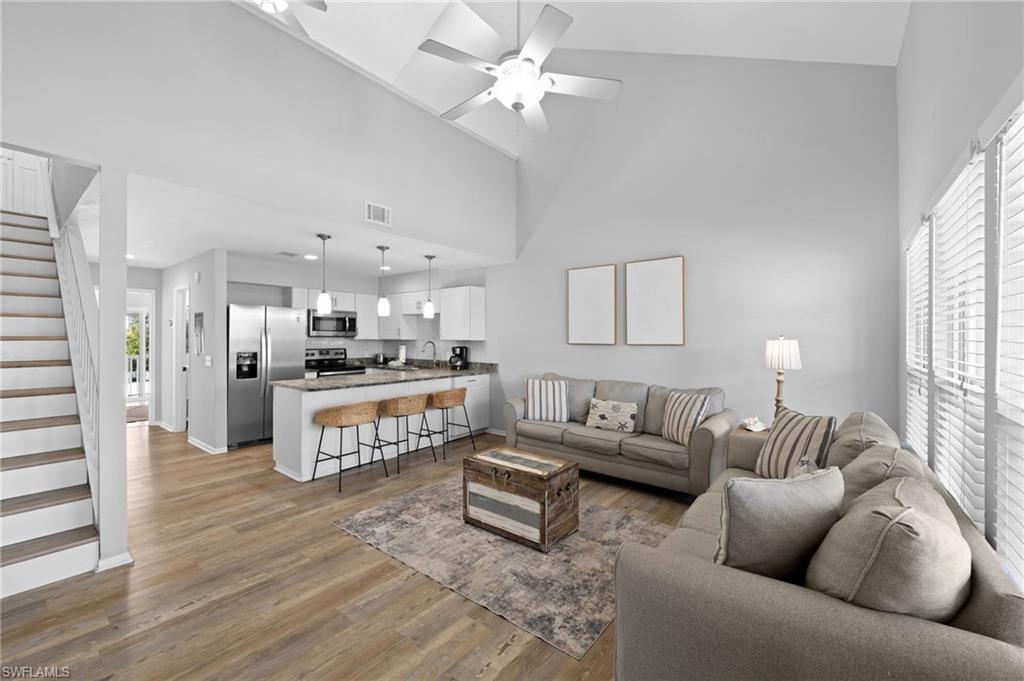 Image 2: Living room featuring stairs, high vaulted ceiling, light wood-style flooring, and a ceiling fan