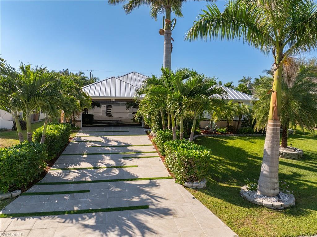 Image 1: Frontal view of home with a front yard tiled driveway and glass garage door