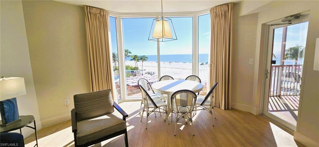 Image 4: Dining area featuring expansive windows, light wood-style flooring, and view of water and beach