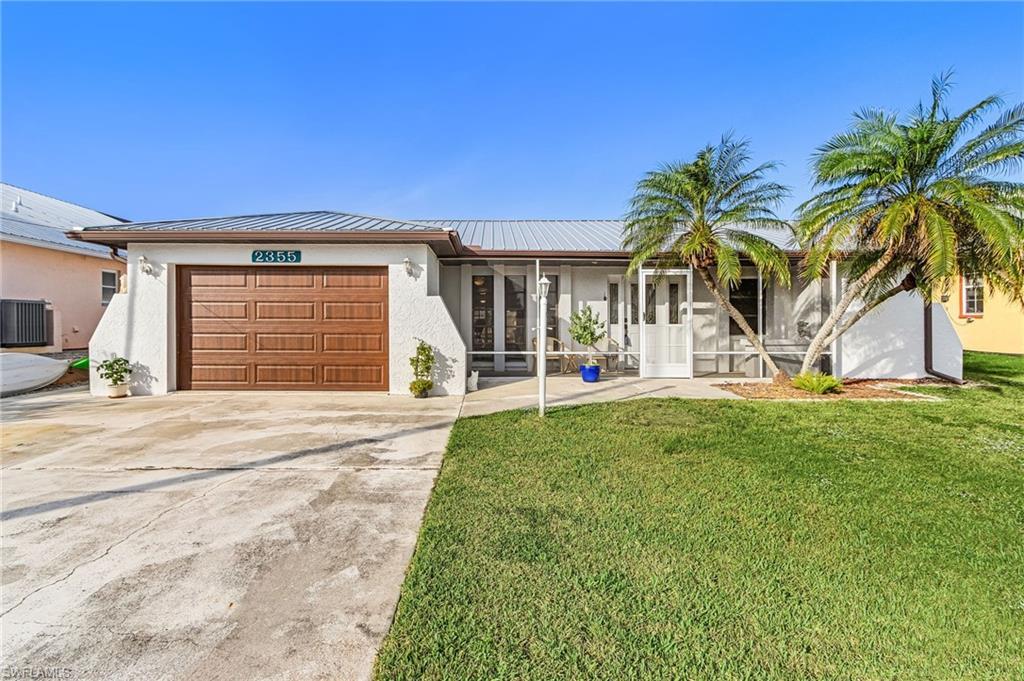 Image 1: Ranch-style home featuring stucco siding, a front yard, an attached garage, and driveway