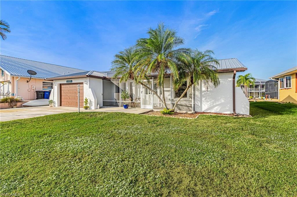 Image 3: View of front of house featuring a front lawn, a garage, driveway, and stucco siding