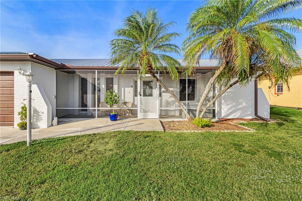 Image 4: Front view of property featuring a lawn, stucco siding, a screened porch, and a metal roof
