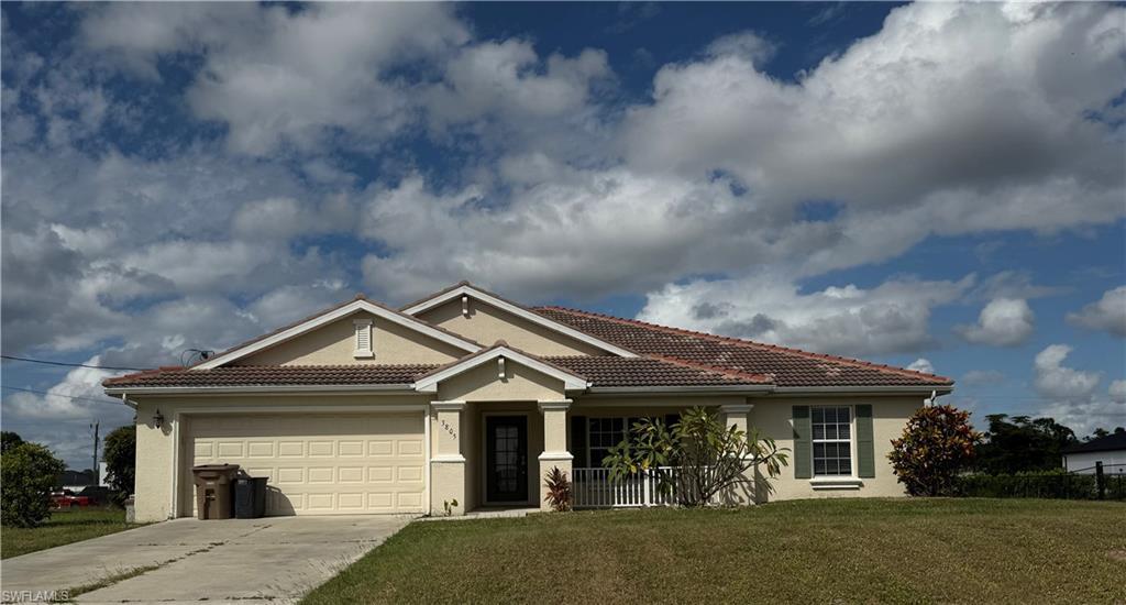 Image 1: View of front of property with a tiled roof, stucco siding, a front lawn, concrete driveway, and a garage