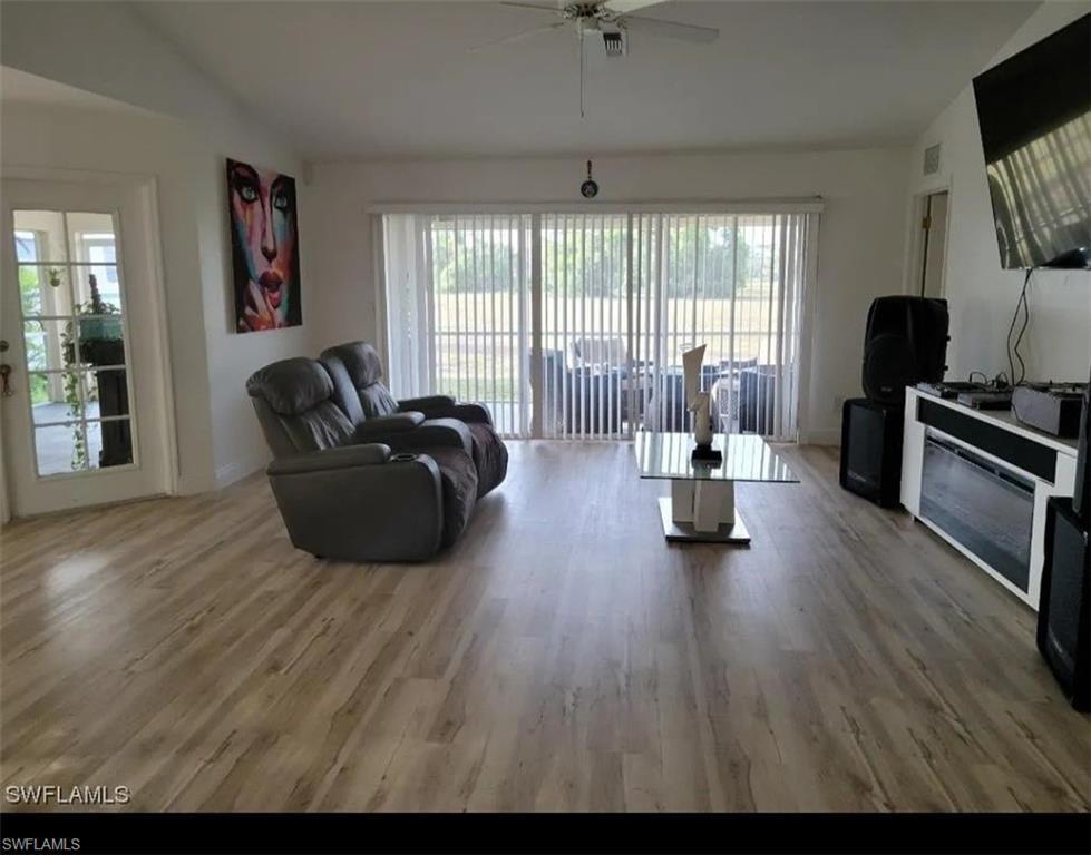 Image 3: Living area with light wood-style flooring, plenty of natural light, ceiling fan, and vaulted ceiling