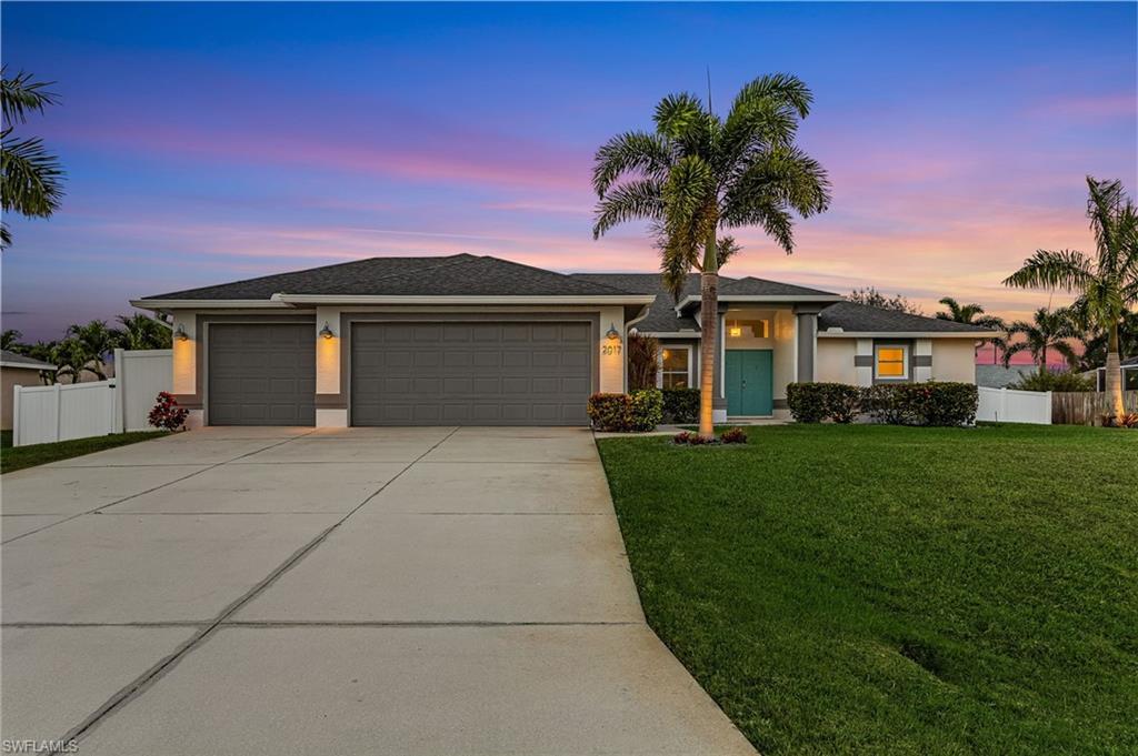 Image 2: View of front of property with a garage, driveway, stucco siding, and a shingled roof