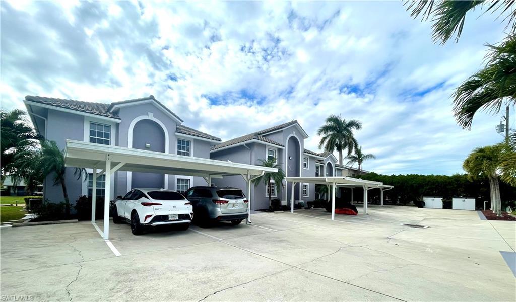 Image 2: View of front facade with stucco siding, a tile roof, and covered parking