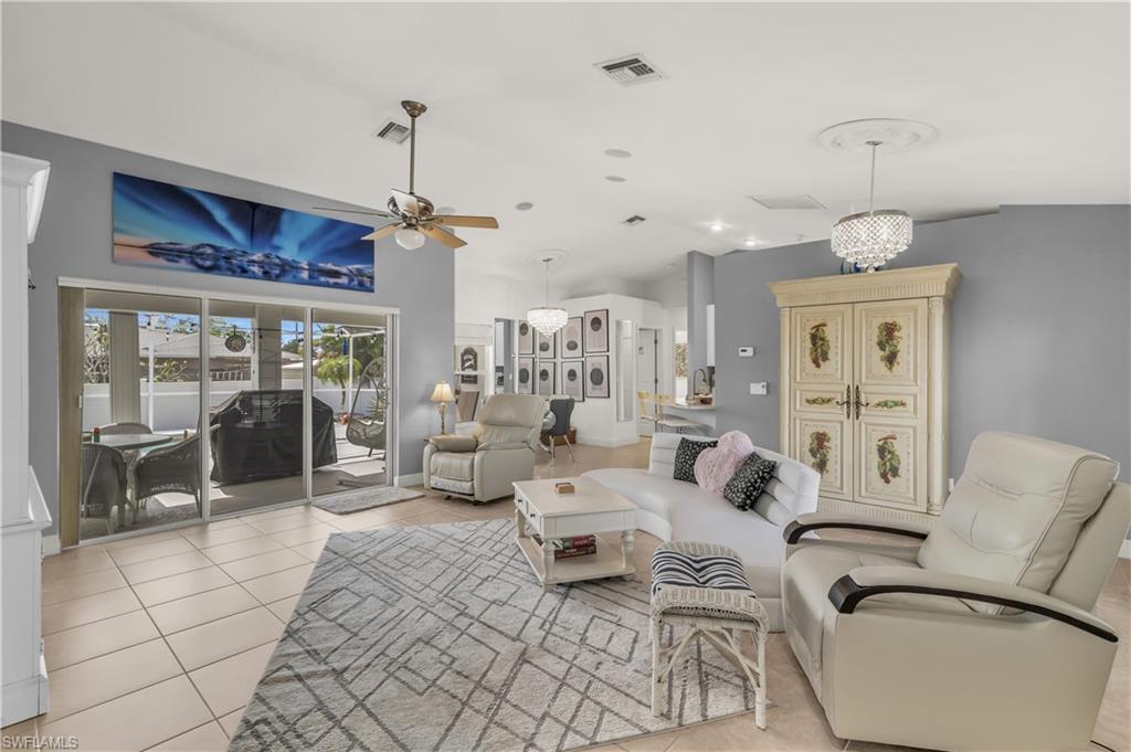 Image 2: Living area featuring vaulted ceiling, light tile patterned floors, a ceiling fan, and a chandelier