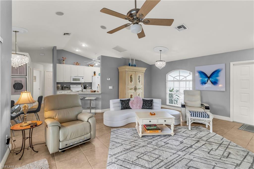 Image 3: Living room with hanging lights, light tile patterned floors, vaulted ceiling, and a ceiling fan