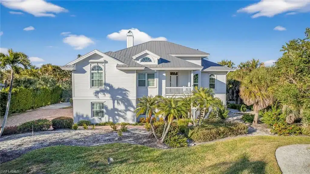 Image 1: Raised beach house with a chimney, a front lawn, and a metal roof