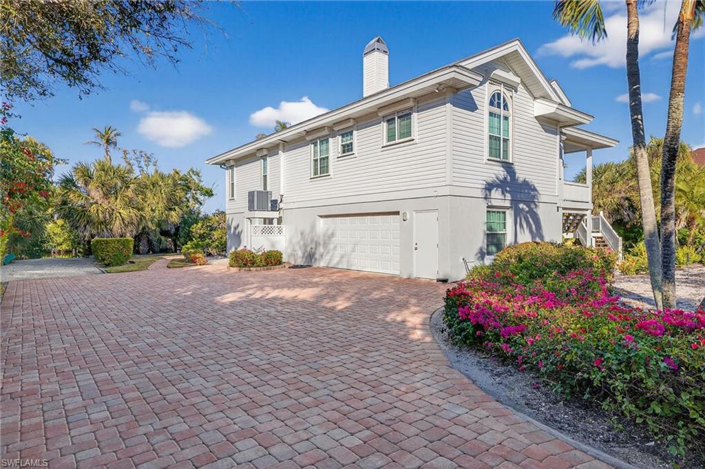Image 2: View of home's exterior with an attached garage, stucco siding, decorative driveway, and a chimney