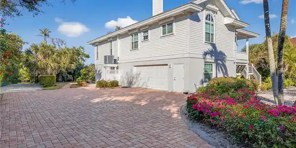Image 2: View of home's exterior with an attached garage, stucco siding, decorative driveway, and a chimney