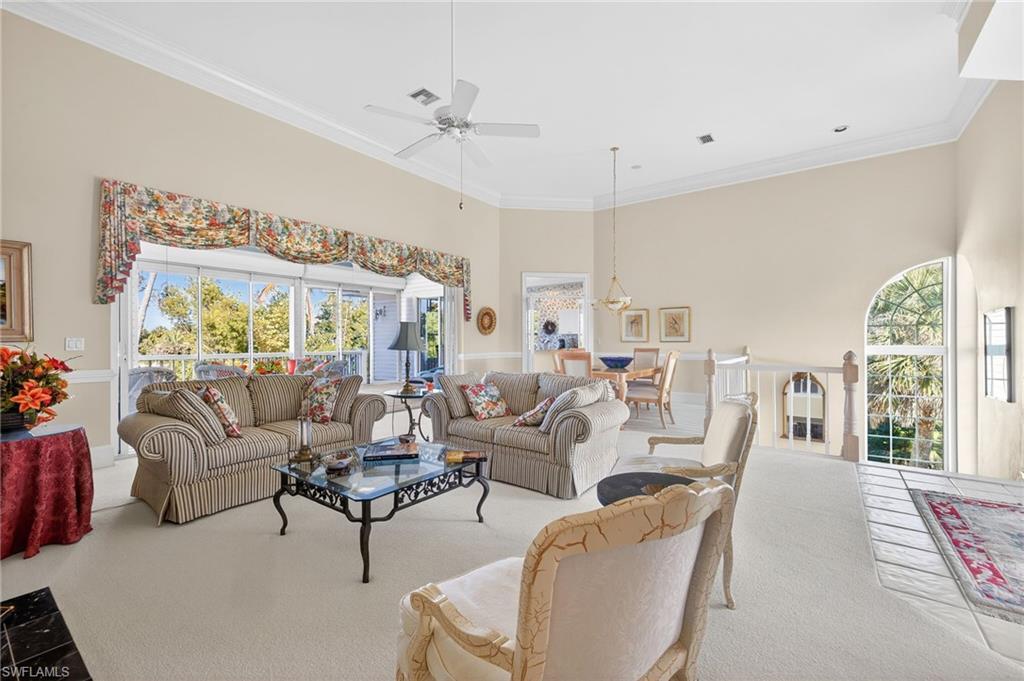 Image 3: Carpeted living room featuring a ceiling fan, crown molding, plenty of natural light, and a high ceiling