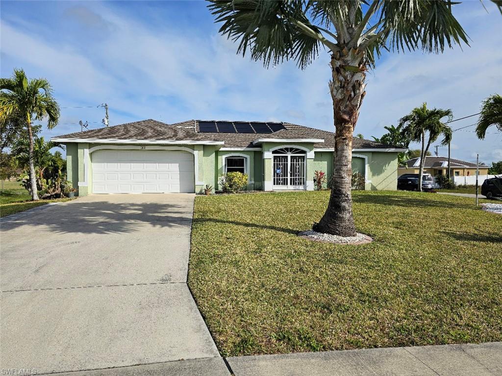 Image 2: Single story home featuring stucco siding, roof mounted solar panels, an attached garage, and driveway
