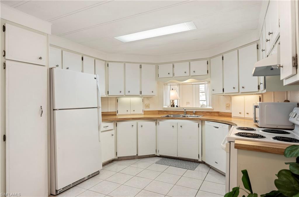 Image 4: Kitchen featuring white appliances, light countertops, white cabinets, and light tile patterned floors