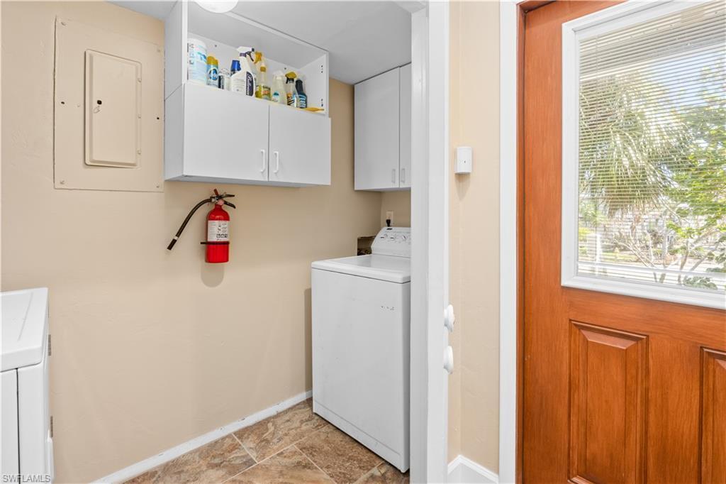 Image 4: Laundry area featuring cabinet space, electric panel, washing machine and dryer, and stone finish flooring