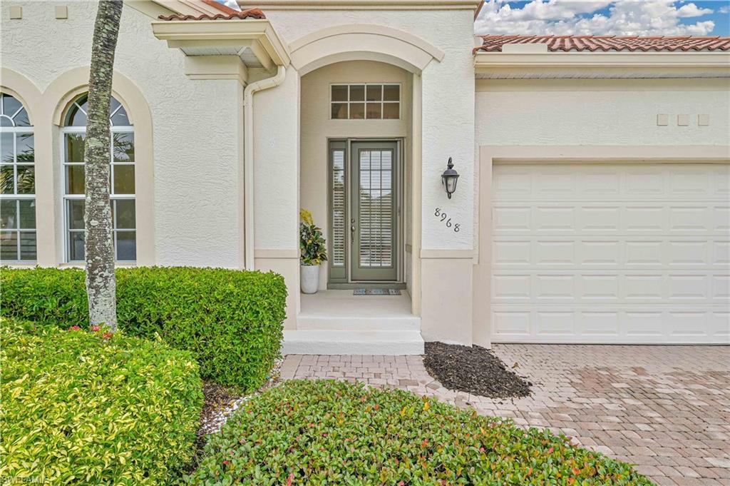 Image 3: Doorway to property featuring a tile roof, stucco siding, driveway, and a garage