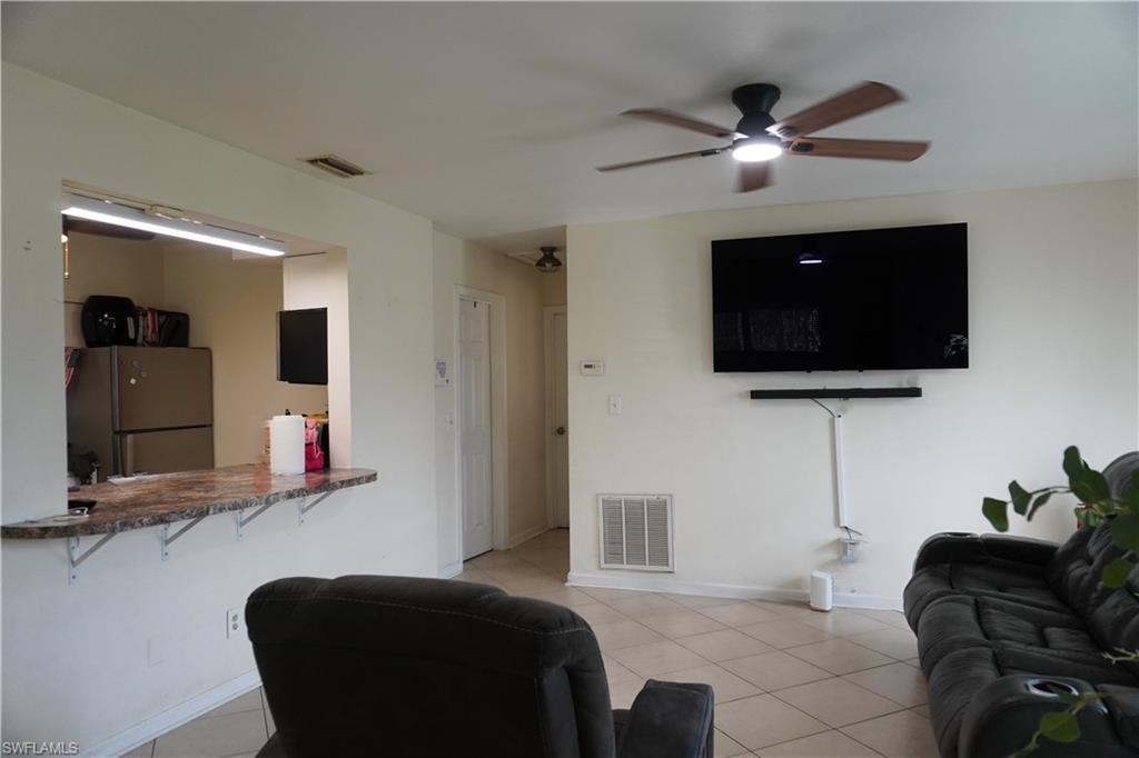 Image 2: Living room with ceiling fan and light tile patterned flooring