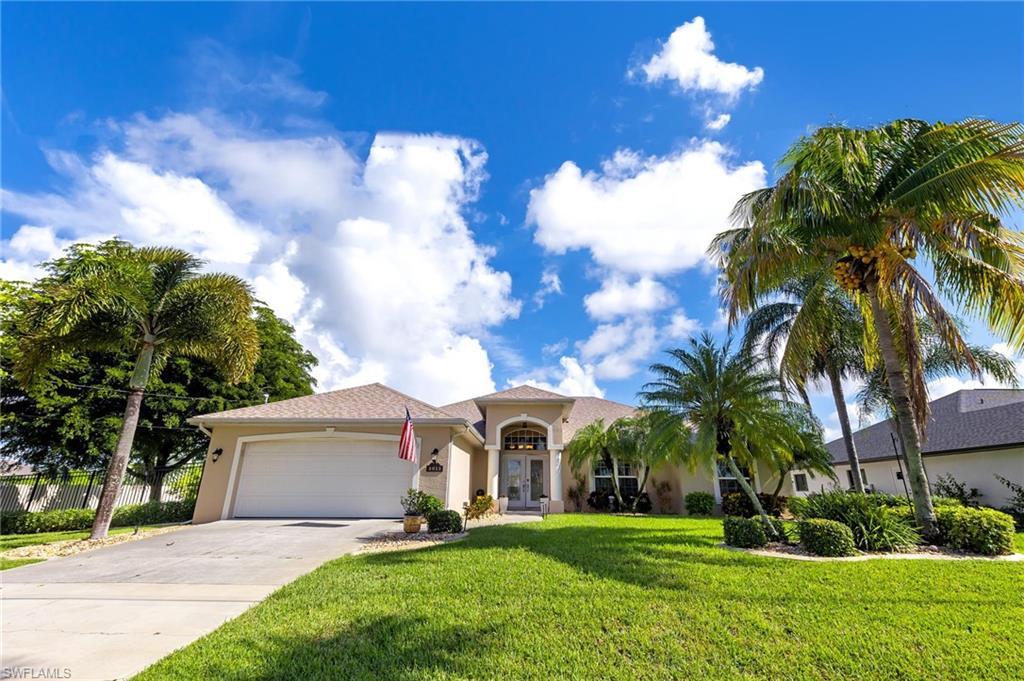 Image 1: View of front of home featuring stucco siding, driveway, a garage, and a front lawn