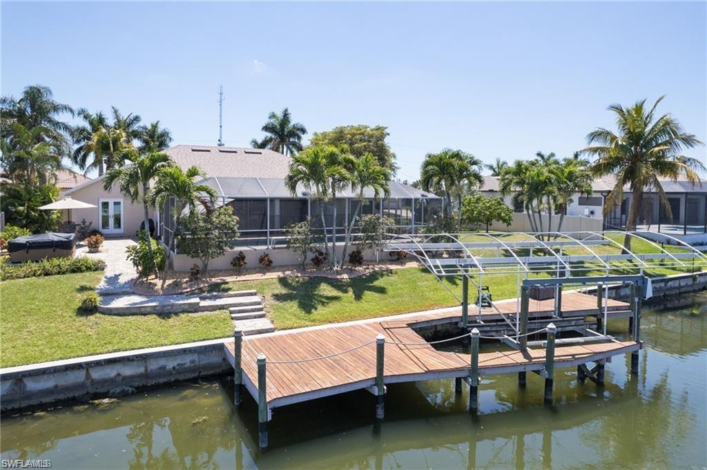 Image 2: Dock area featuring a water view, boat lift, an oversized yard, and screen enclosure around pool.