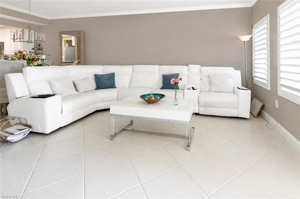 Image 3: Living area featuring large format tile flooring, a neutral wall color, crown molding, and plantation shutters