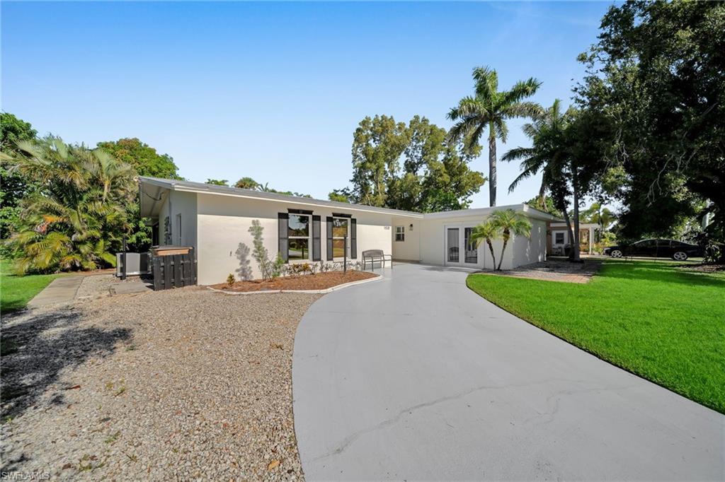 Image 1: White stucco exterior with black window shutters and a curved paved driveway
