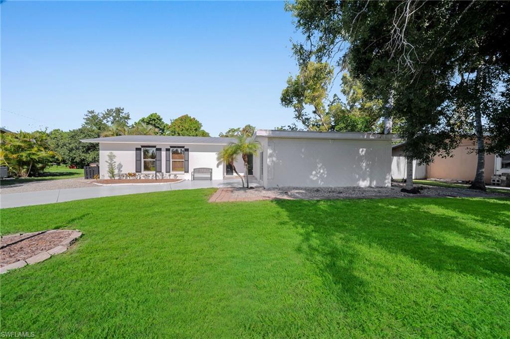 Image 2: Single-story residence featuring a gray roofline, white exterior, and dark window shutters