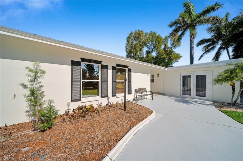 Image 4: Light-colored stucco exterior featuring dark shutters, a low-sloped roofline, and mature landscaping