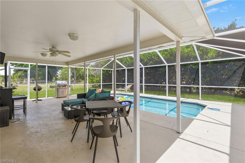 Image 3: Screened outdoor living area featuring a covered patio, ceiling fan, and in-ground swimming pool