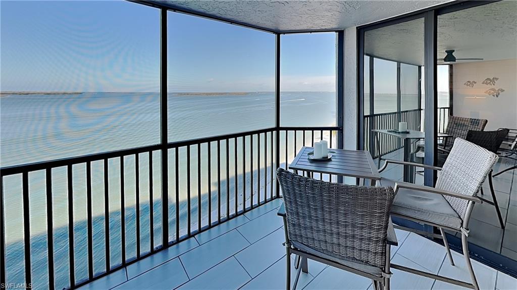 Image 3: Screened balcony featuring expansive water scenery, tile flooring, black metal railings, and sliding glass doors
