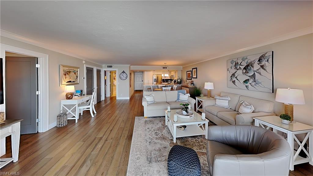 Image 4: Spacious living area featuring wood-finish flooring, light-toned walls, and crown molding