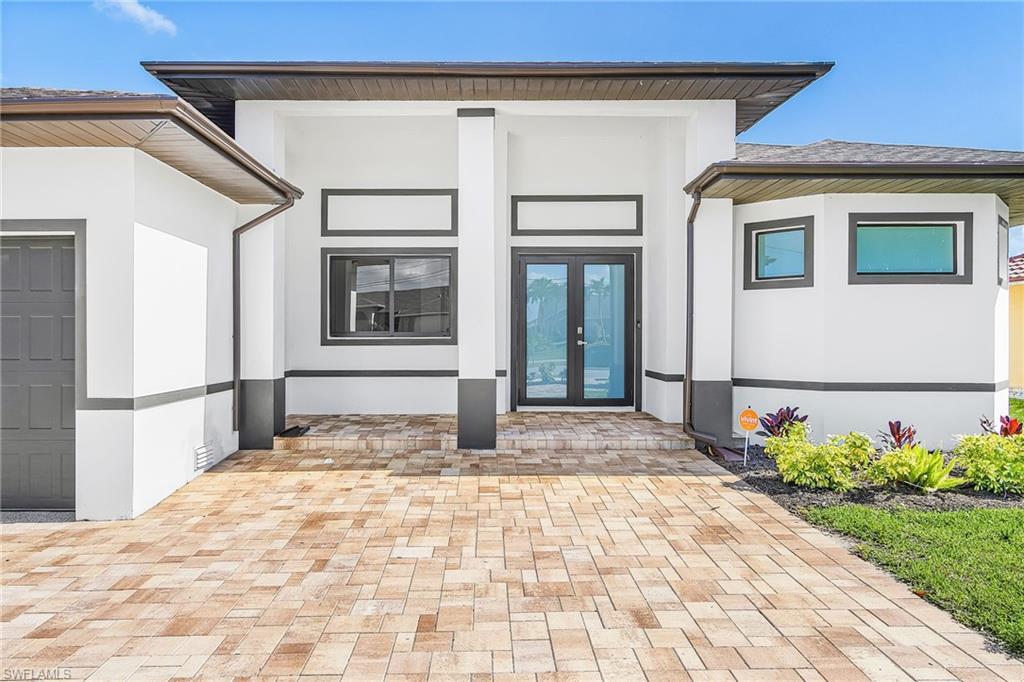 Image 4: Contemporary exterior featuring a paver driveway, double-door entry, a two-tone exterior finish, and integrated landscaping