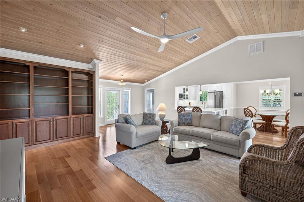 Image 4: Expansive living area featuring vaulted wood-plank ceilings, recessed lighting, and rich wood-finish flooring