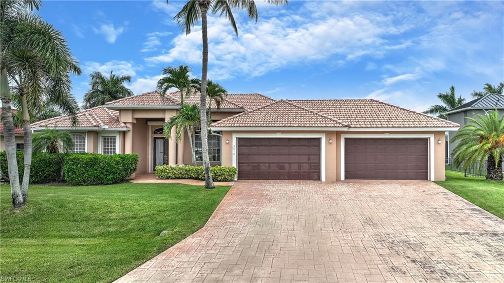 Image 2: Stucco exterior residence featuring a tile roof and a stamped concrete driveway