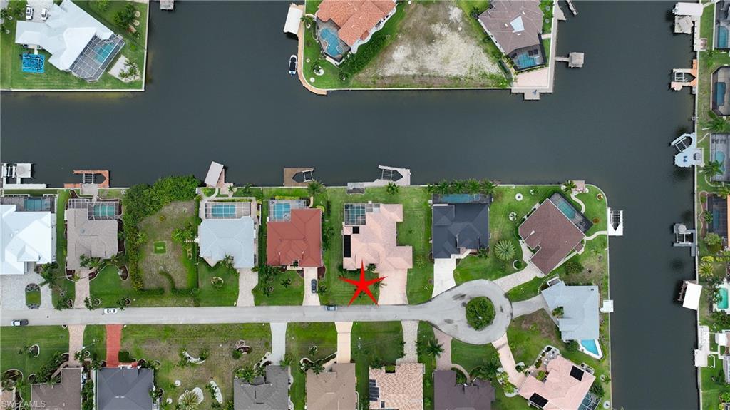Image 3: Waterfront property featuring a private boat dock, concrete drive, and a manicured lawn