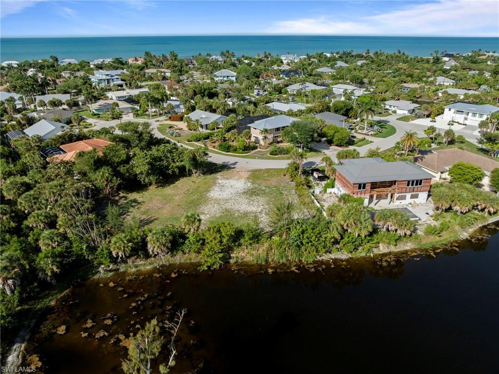 Image 1: Expansive lot featuring a cleared building envelope, mature tropical landscaping, and a waterfront boundary