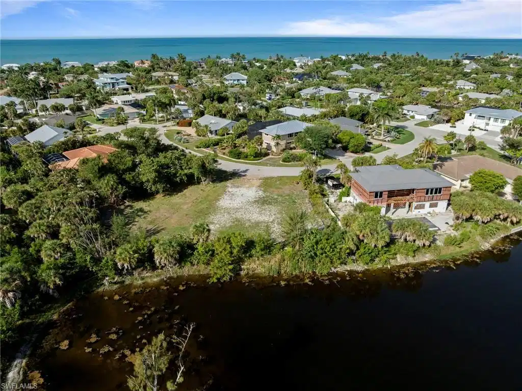 Image 1: Expansive lot featuring a cleared building envelope, mature tropical landscaping, and a waterfront boundary