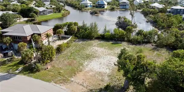 Image 3: Expansive undeveloped lot featuring partial vegetation and a paved street frontage