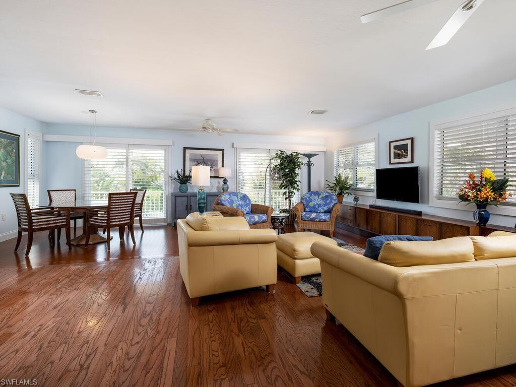 Image 4: Living area with dark wood flooring, ceiling fan, and plenty of natural light