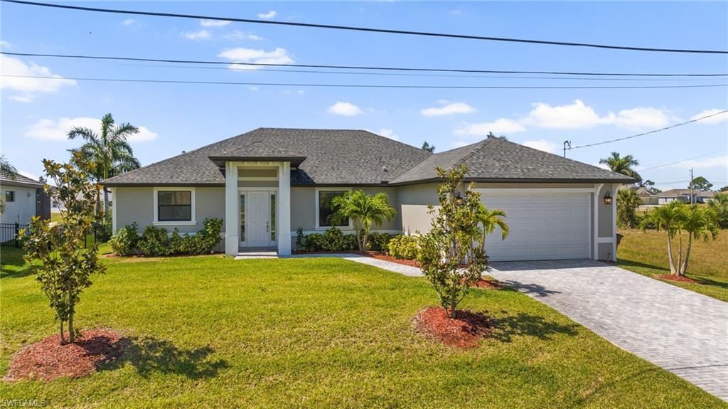 Image 2: View of front of house featuring a front yard, an attached garage, stucco siding, decorative driveway, and roof with shingles