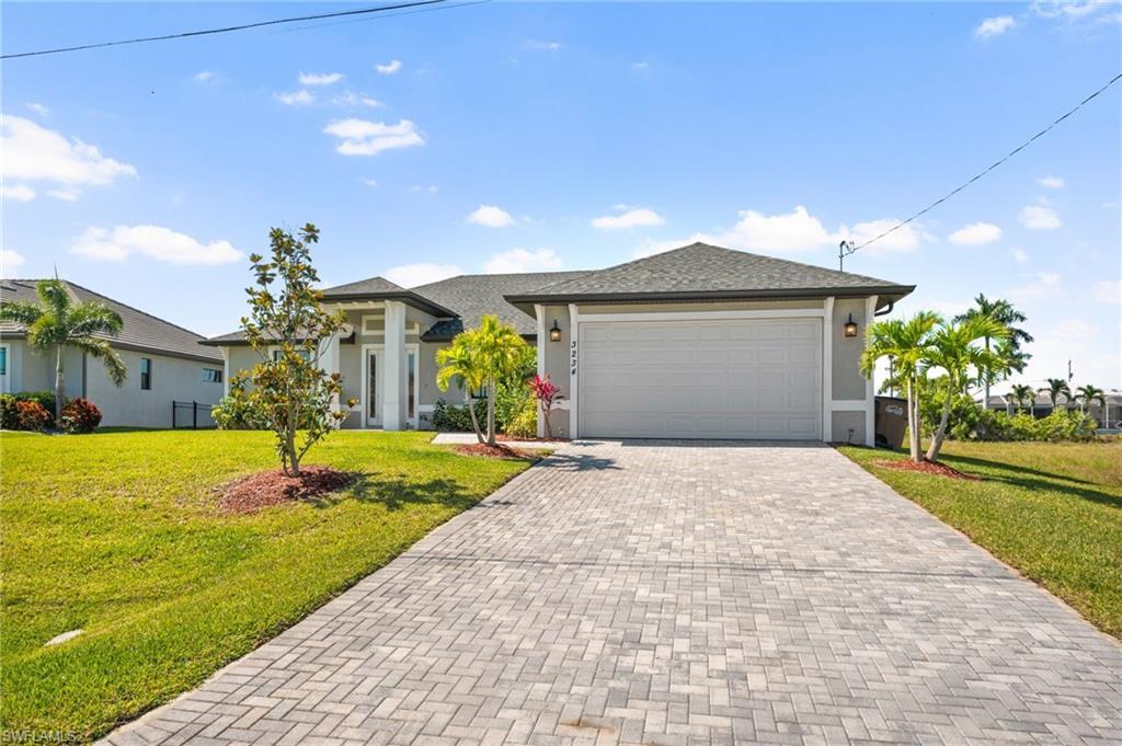 Image 3: View of front of property with a front yard, a garage, decorative driveway, and stucco siding