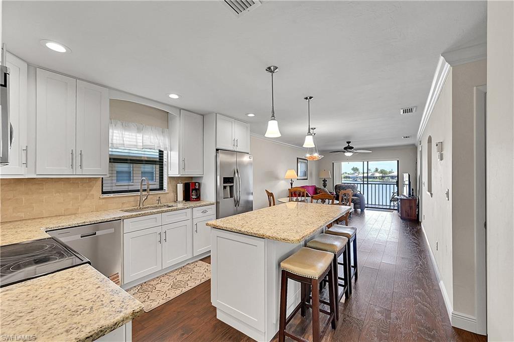 Image 3: Kitchen with stainless steel appliances, a sink, crown molding, a kitchen island, and tasteful backsplash