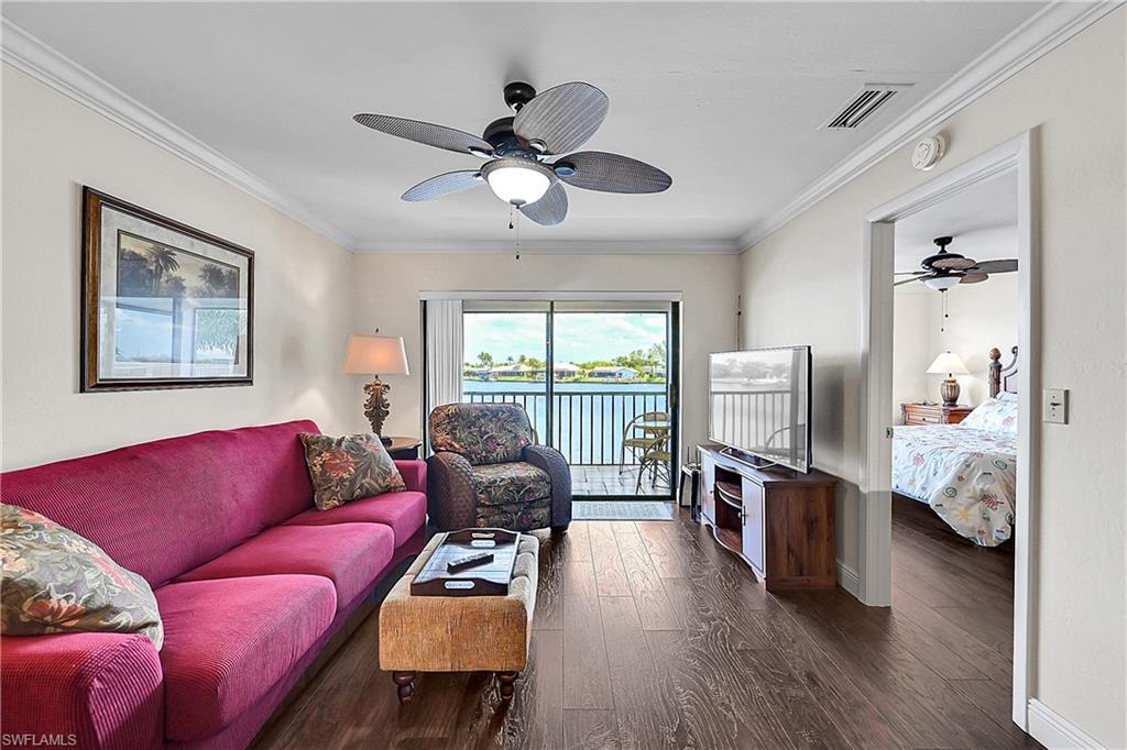 Image 4: Living area with ceiling fan, wood-style flooring, baseboards, and ornamental molding
