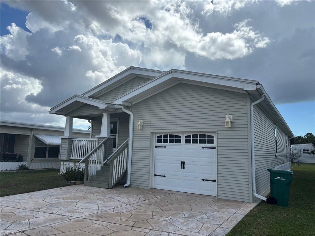 Image 2: View of front of property featuring a garage, driveway, a front yard, and covered porch