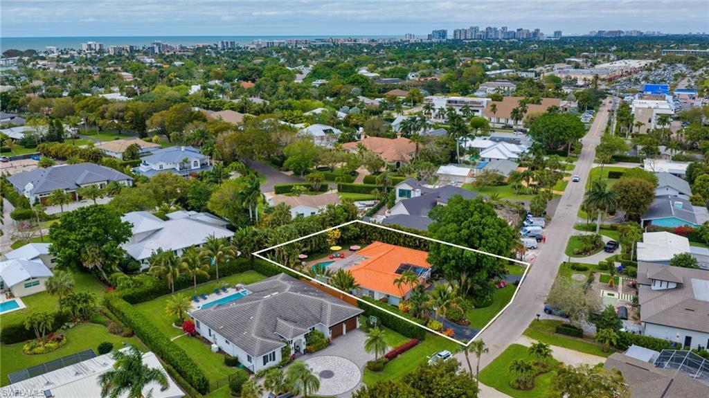 Image 3: Aerial view of residential area with property parcel outlined, city skyline, and a nearby body of water