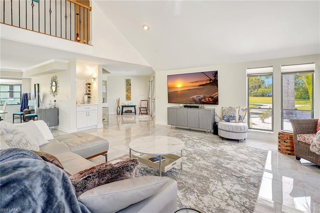 Image 4: Living room with marble finish floor, a towering ceiling, and recessed lighting