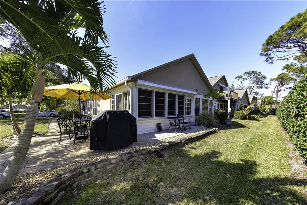 Image 2: Exterior featuring a paver patio, mature palm trees, a spacious lawn, and a low stone retaining wall