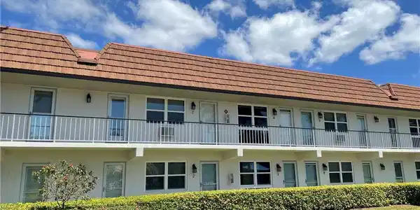 Image 2: Exterior fa&ccedil;ade featuring a terra cotta tile roof, multiple residential units, and a second-story balcony with metal railings