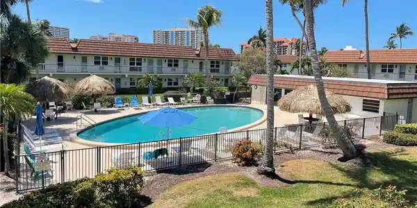 Image 3: Outdoor swimming pool area featuring a freeform pool, surrounding lounge seating, and two tiki-style cabanas