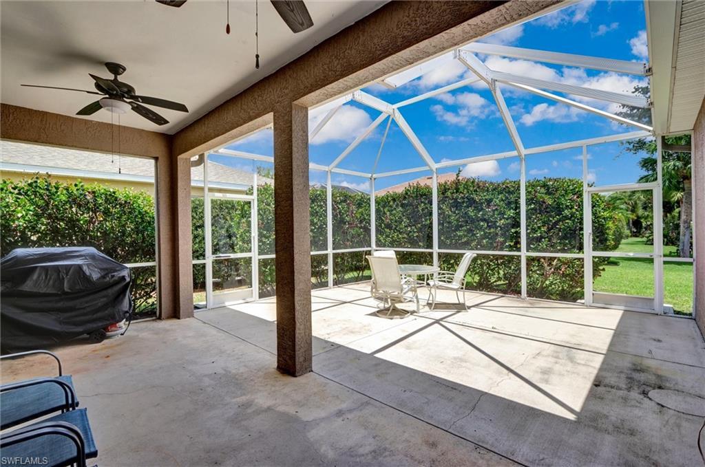 Image 4: Expansive screened lanai featuring a vaulted cage, concrete flooring, and an attached covered patio with a ceiling fan
