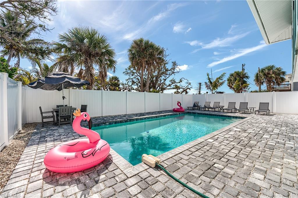 Image 3: View of pool featuring a patio area, a fenced backyard, and outdoor dining space- Virtually Edited Image